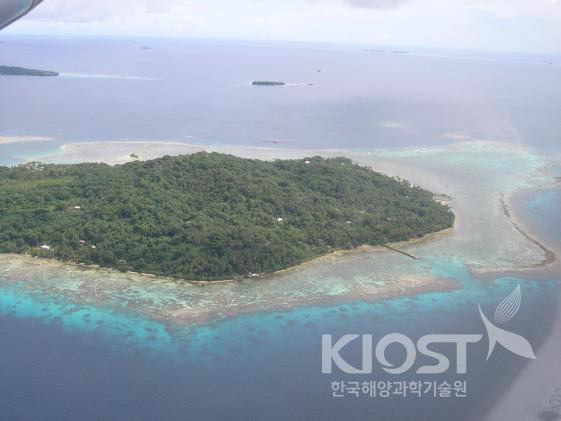 하늘에서 바라본 열대의 섬 주변에 테두리를 이룬 산호초가 보인다 의 사진