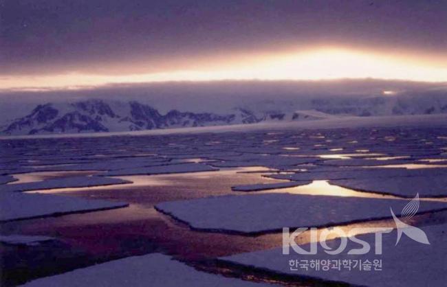 암벽과 빙벽으로 된 남극반도 서쪽 알렉산더 섬 해안의 황혼 의 사진
