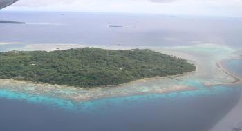 하늘에서 바라본 열대의 섬 주변에 테두리를 이룬 산호초가 보인다